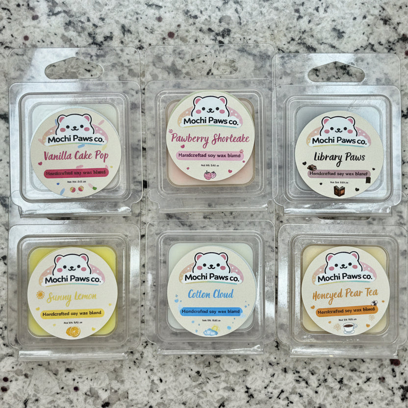 Six wax melts in clear packaging with 'Mochi Paws co.' labels on a granite countertop.