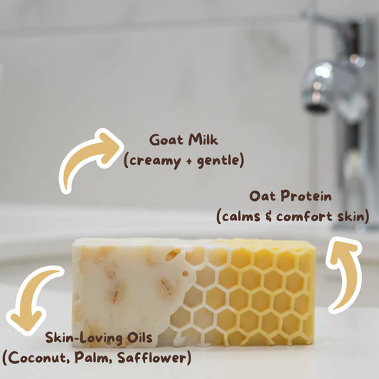 Bar of soap with text highlighting goat milk, oat protein, and skin-loving oils on a bathroom counter.