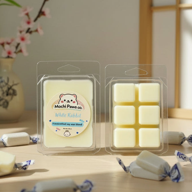 Mochi Paws co. white rabbit soap bars in clear packaging on a wooden surface with a decorative background.