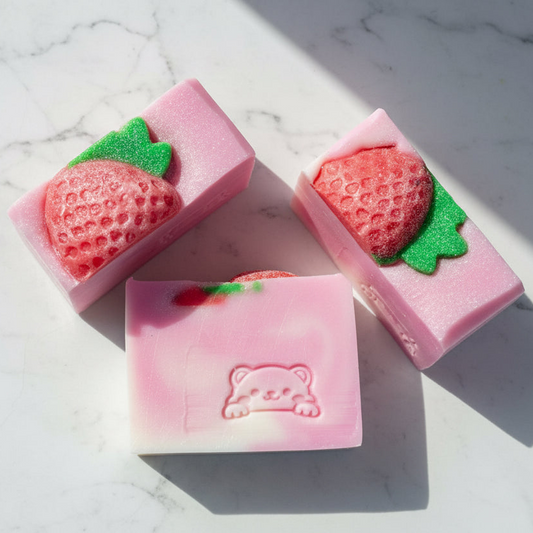 Three strawberry-shaped soaps on a marble surface