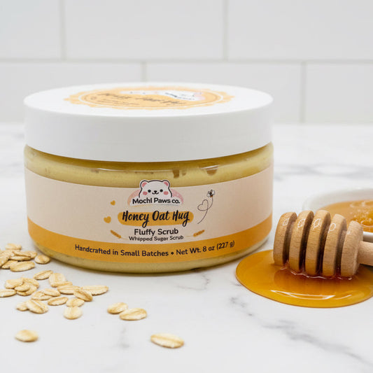 Jar of Mochi Paws Honey Oat Hug Fluffy Scrub with honey and oats on a marble surface.