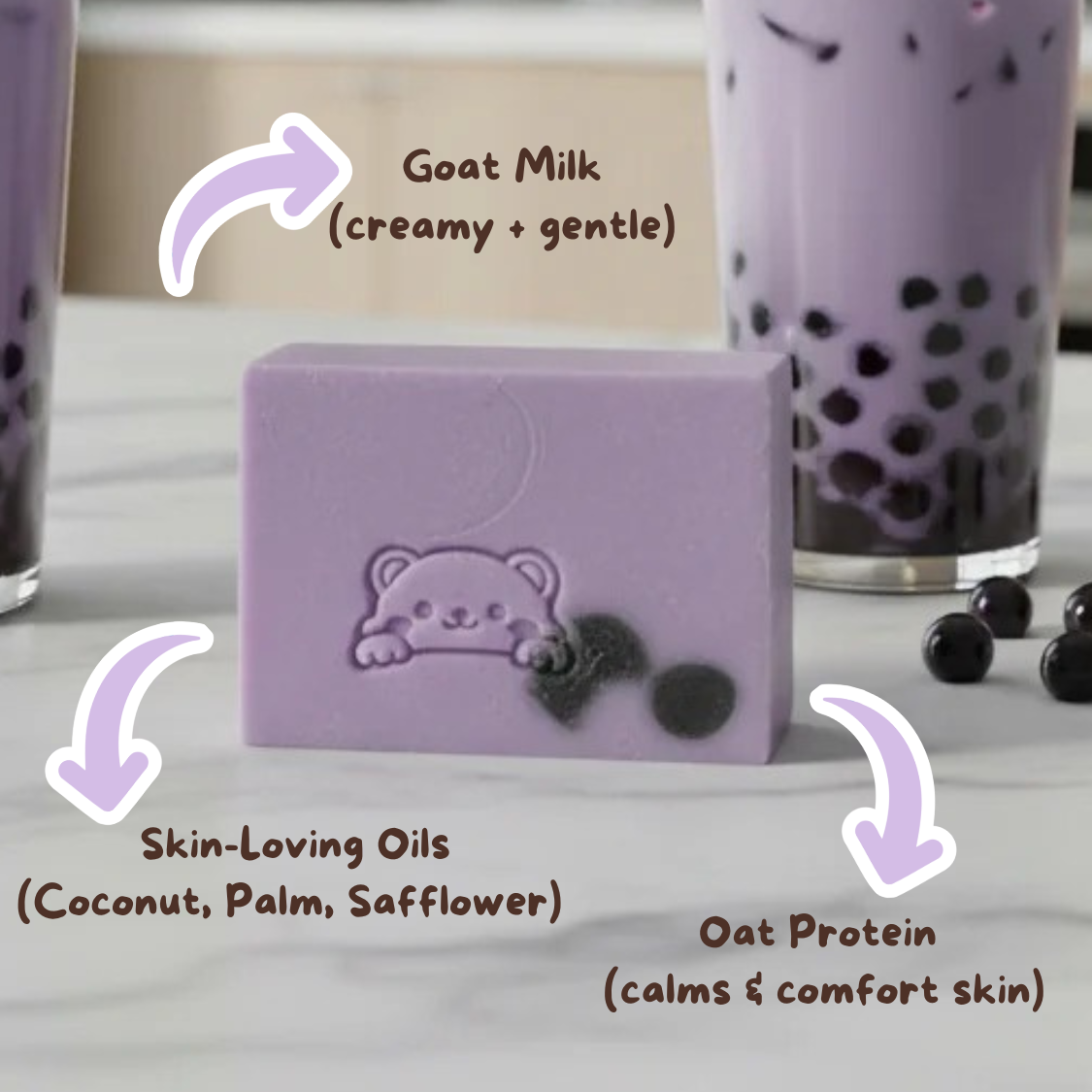 Purple soap bar with bear design on a white surface, surrounded by black tapioca pearls and a glass of bubble tea.