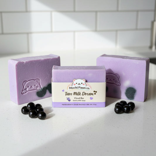 Three purple soap bars with a packaging label on a gray surface